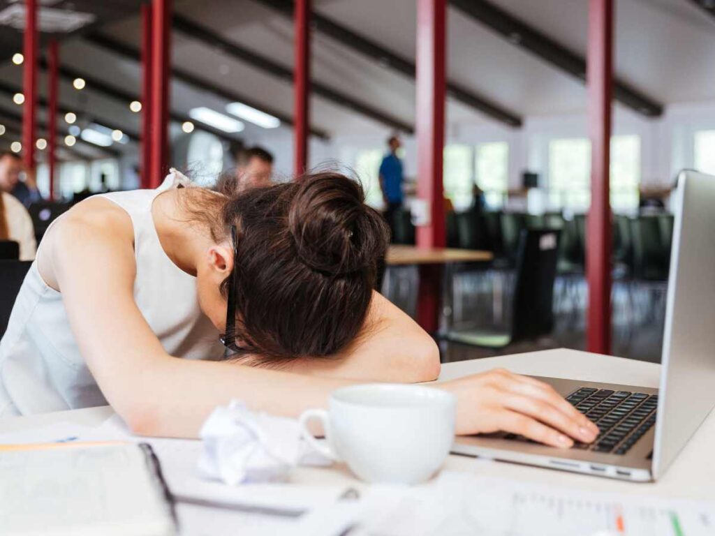 Tired lady lying on table with her laptop