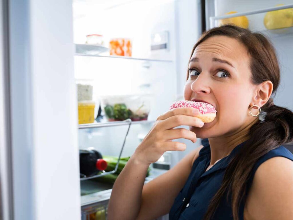 girl eating food from the fridge