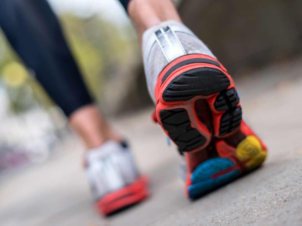 legs of athlete walking backwards on road