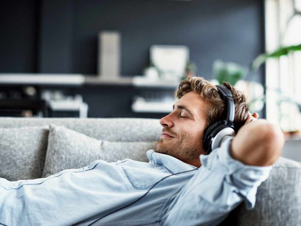 man sleeping on sofa with his headphones