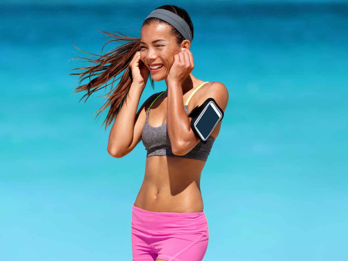 lady wearing bluetooth earbuds at a beach