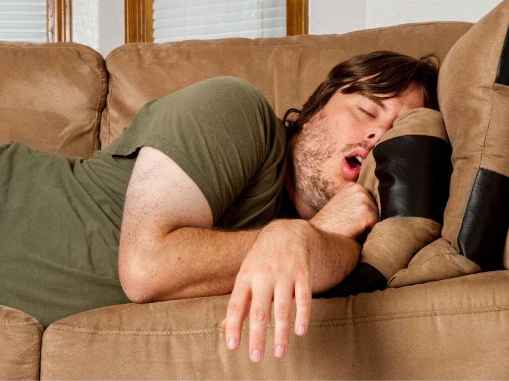 man taking power nap on a sofa at home